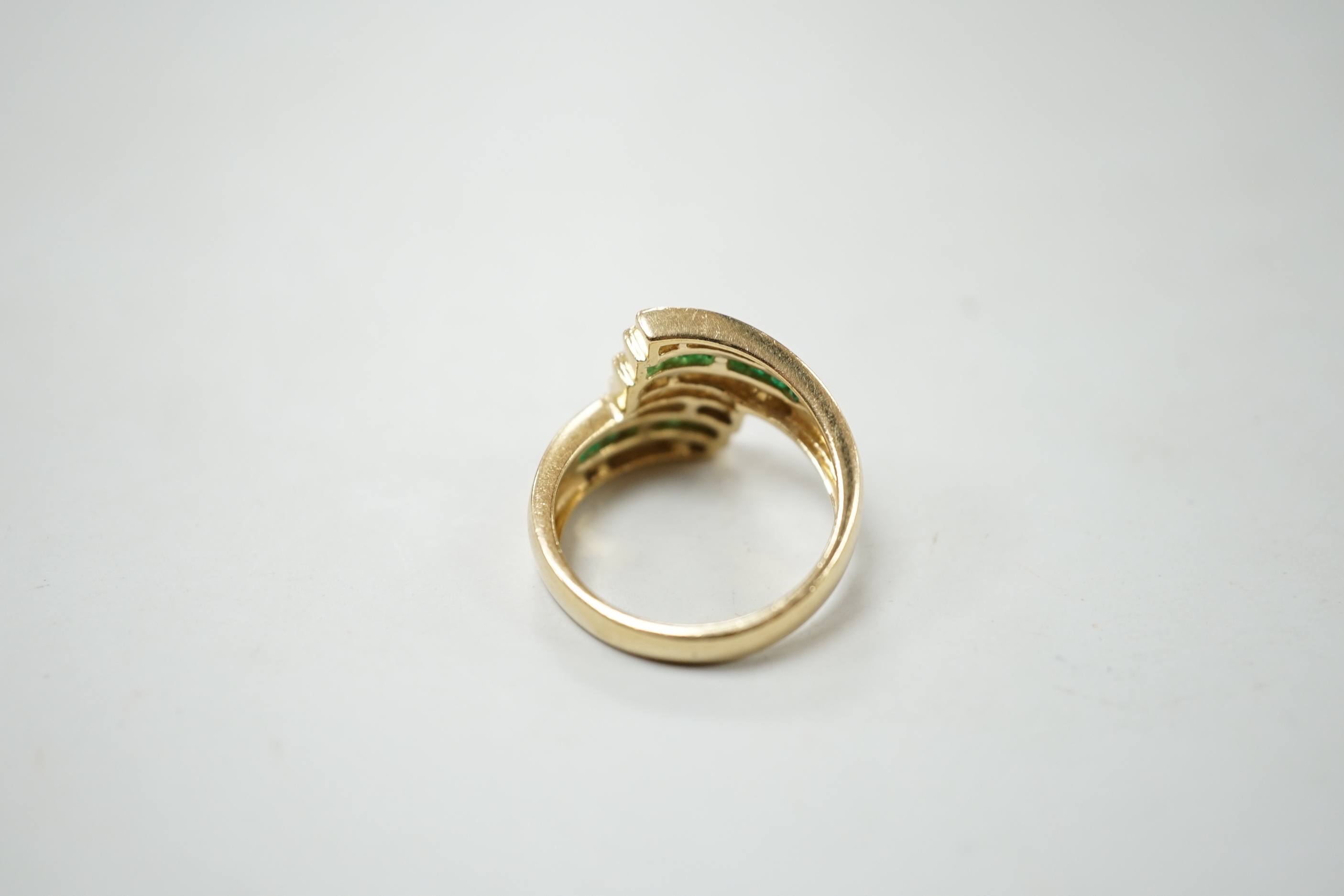 A modern 14k yellow metal, emerald and diamond chip set triple row crossover ring, size O, gross weight 5.4 grams.